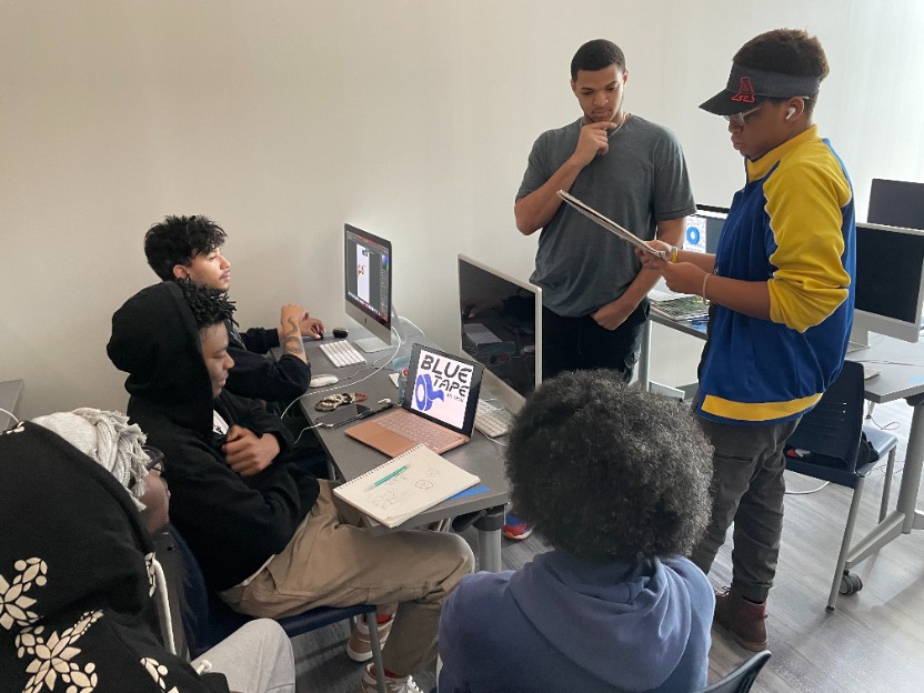 graphic design students gather around a project in bessemer